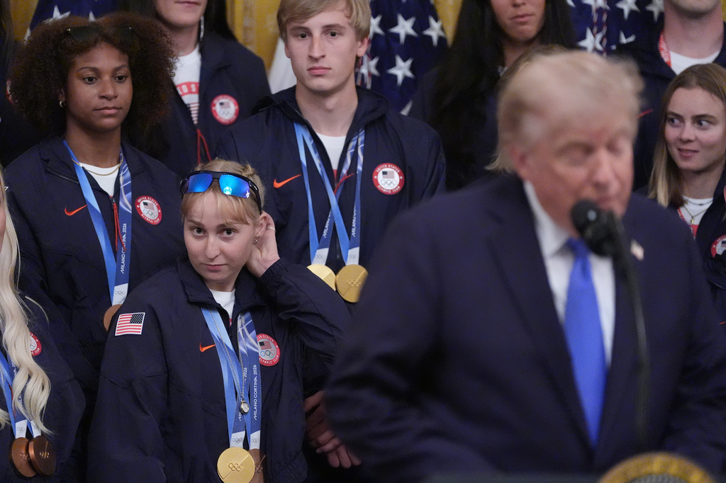 President Donald Trump speaks as Elizabeth Lemley, lower center, and Jordan Stolz, top center, watch, during an event for Olympic athletes, coaches, staff, and representatives from Team USA in the East Room of the White House, Thursday, Aug. 6, 2026, in Washington. (AP Photo/Alex Brandon)