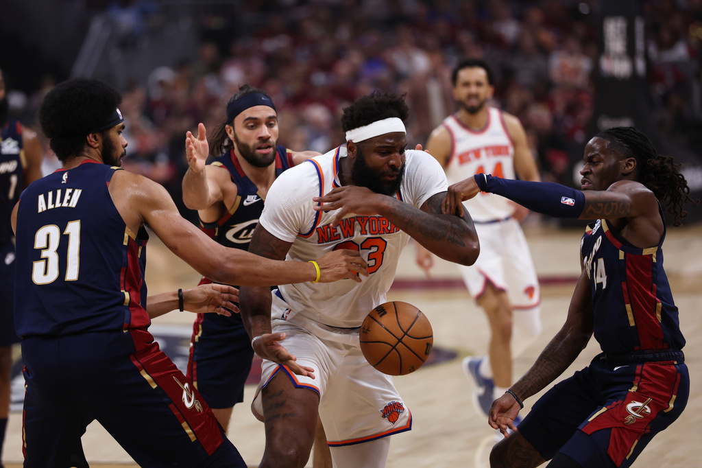 Cleveland Cavaliers center Jarrett Allen (31), guard Keon Ellis (14), and New York Knicks center Mitchell Robinson (23) reach for a rebound during the first half of Game 4 in the Eastern Conference finals NBA basketball playoffs series in Cleveland, Monday, May 25, 2026. (AP Photo/Tim Phillis)