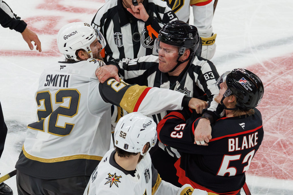 Vegas Golden Knights' Cole Smith (22) and Carolina Hurricanes' Jackson Blake (53) scuffle as an official tries to separate them during the second period of Game 5 of the NHL hockey Stanley Cup Final series in Raleigh, N.C., Thursday, June 11, 2026. (AP Photo/Ben McKeown)
