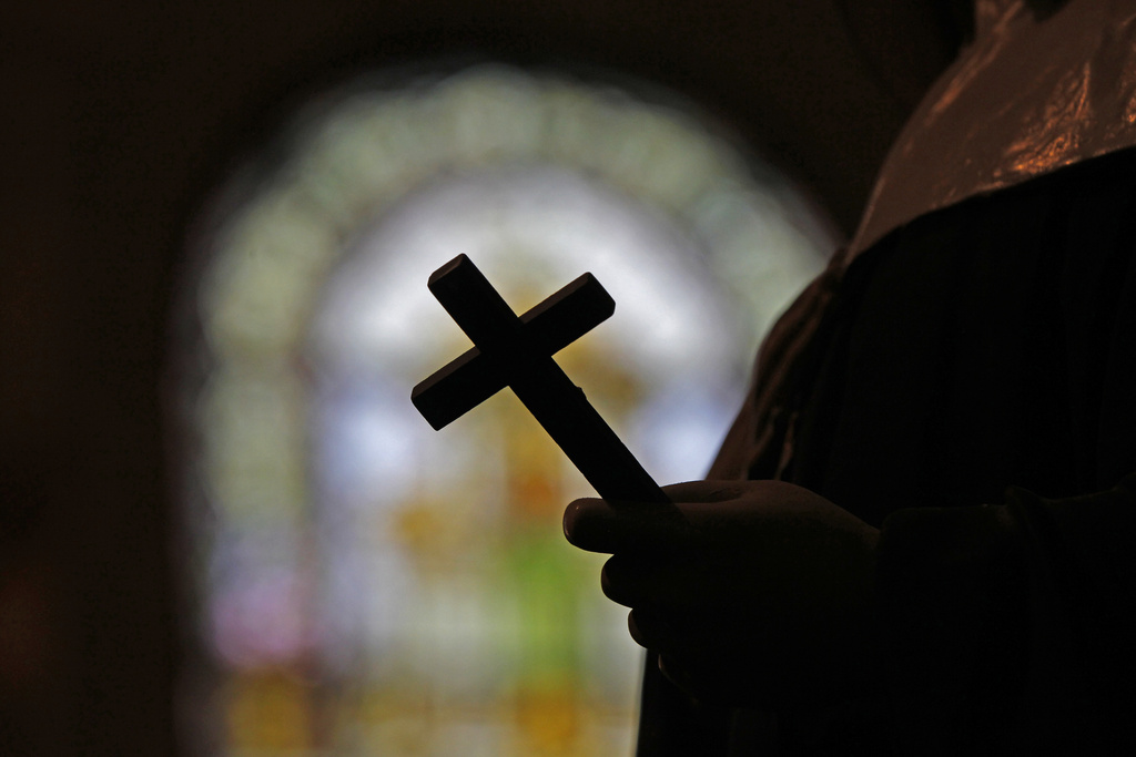 FILE - A crucifix is silhouetted in front of a stained glass window inside a Catholic Church in New Orleans, Dec. 1 2012. (AP Photo/Gerald Herbert, File)