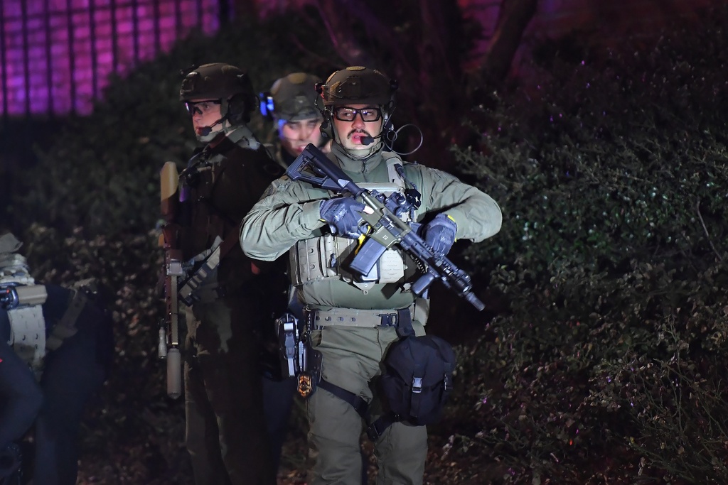 Law enforcement officials carry rifles on a street in a neighborhood near Brown University, Saturday, Dec. 13, 2025, in Providence, R.I. during the investigation of a shooting. (AP Photo/Steven Senne)