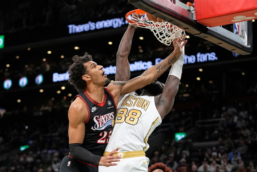 Boston Celtics center Neemias Queta (88) hangs from the rim while defended by Philadelphia 76ers forward Dominick Barlow (25) during the first half of an NBA basketball game, Sunday, March 1, 2026, in Boston. (AP Photo/Robert F. Bukaty)