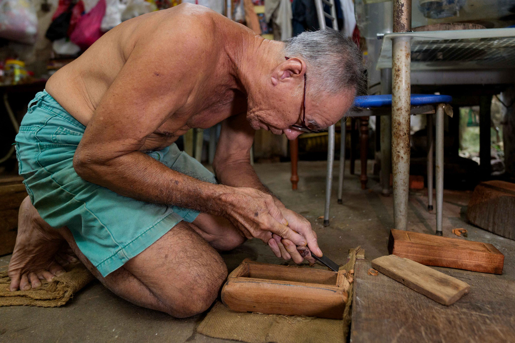Traditional Chinese coffin maker Goh Khuay Par uses a hand tool to shape a miniature coffin at his workshop in Muar, Malaysia, Tuesday, July 14, 2026. (AP Photo/Vincent Thian)