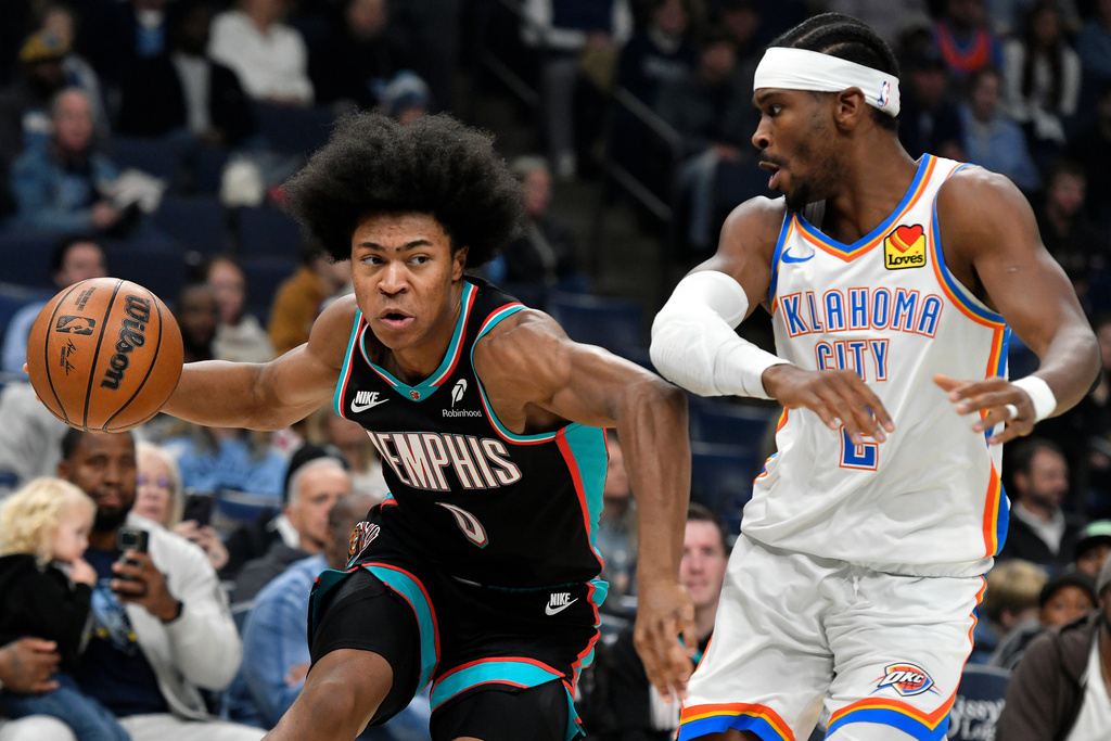 Memphis Grizzlies forward Jaylen Wells, left, handles the ball against Oklahoma City Thunder guard Shai Gilgeous-Alexander, right, in the first half of an NBA basketball game Sunday, Nov. 9, 2025, in Memphis, Tenn. (AP Photo/Brandon Dill)