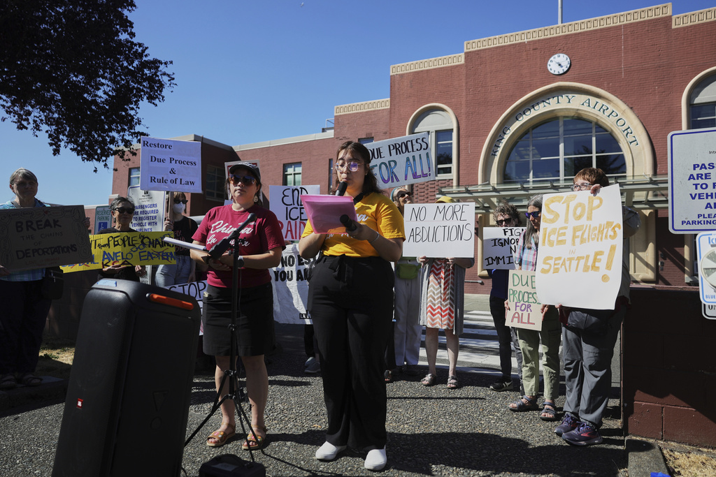 Protesters from the La Resistencia immigrant rights organization speak during a news conference outside of Boeing Field airport in King County, Tuesday, July 15, 2025, in Seattle. (AP Photo/Ryan Sun)
