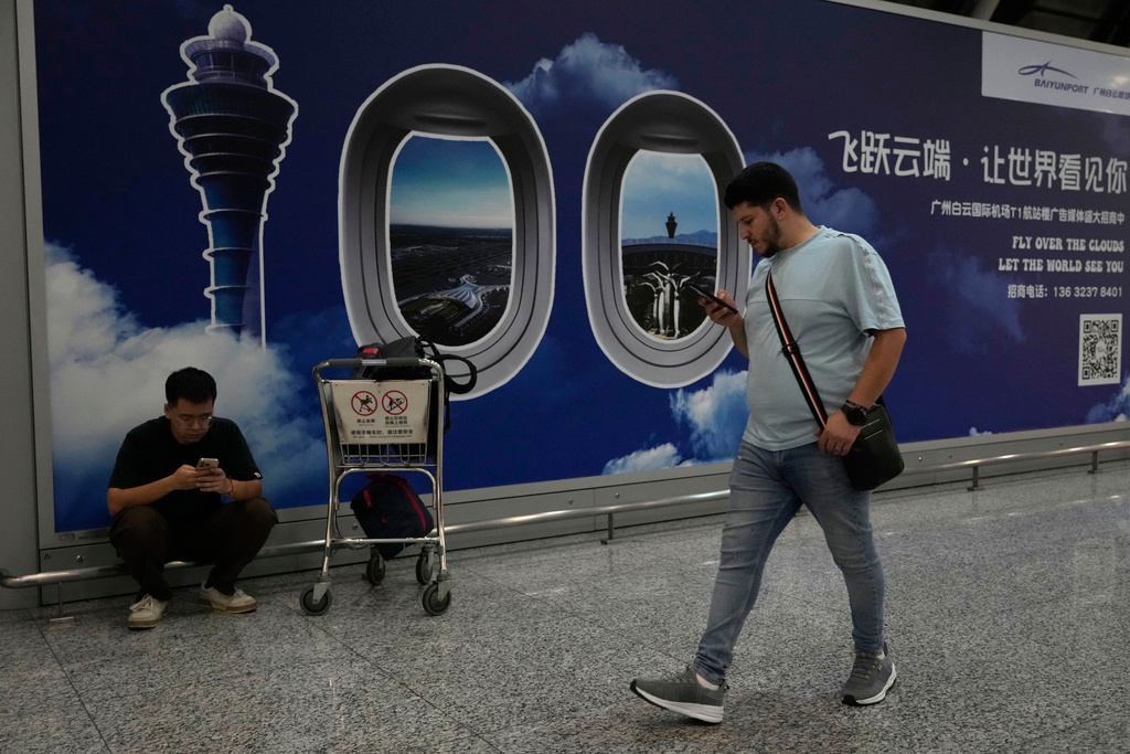 A foreigner walks past a sign board for the Baiyun airport in Guangzhou in southern China's Guangdong province on Nov. 6, 2025. (AP Photo/Ng Han Guan)