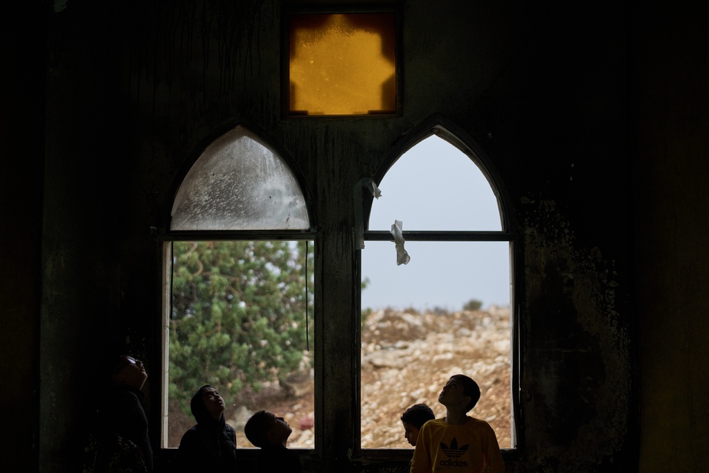 Palestinian youths gather after Friday prayers to inspect a mosque torched and defaced overnight by Israeli settlers in the West Bank village of Deir Istiya, Friday, Nov. 14, 2025. (AP Photo/Leo Correa)