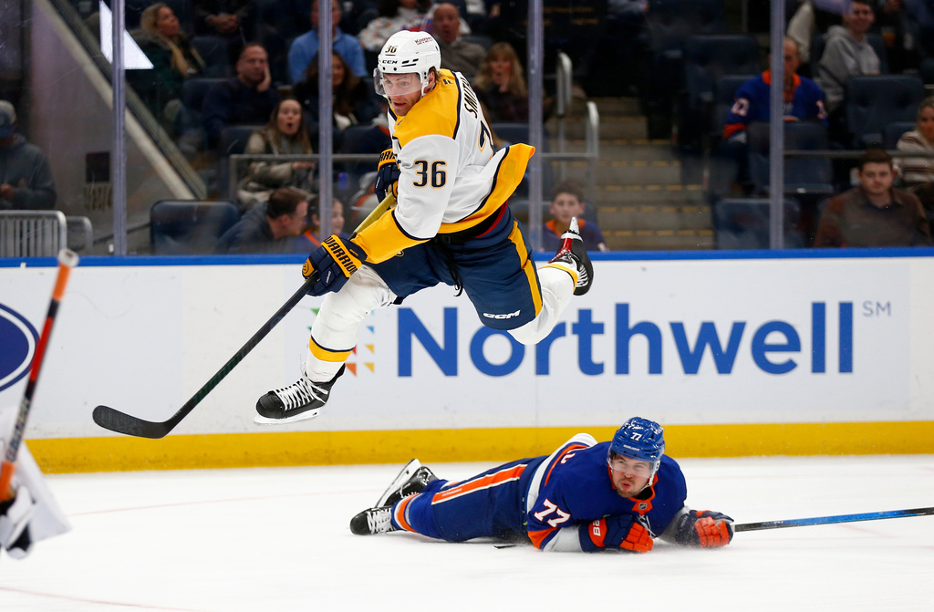 Nashville Predators forward Cole Smith (36) leaps over New York Islanders defenseman Tony DeAngelo (77) during the first period of an NHL hockey game Saturday, Jan. 31, 2026, in Elmont, N.Y. (AP Photo/John Munson)