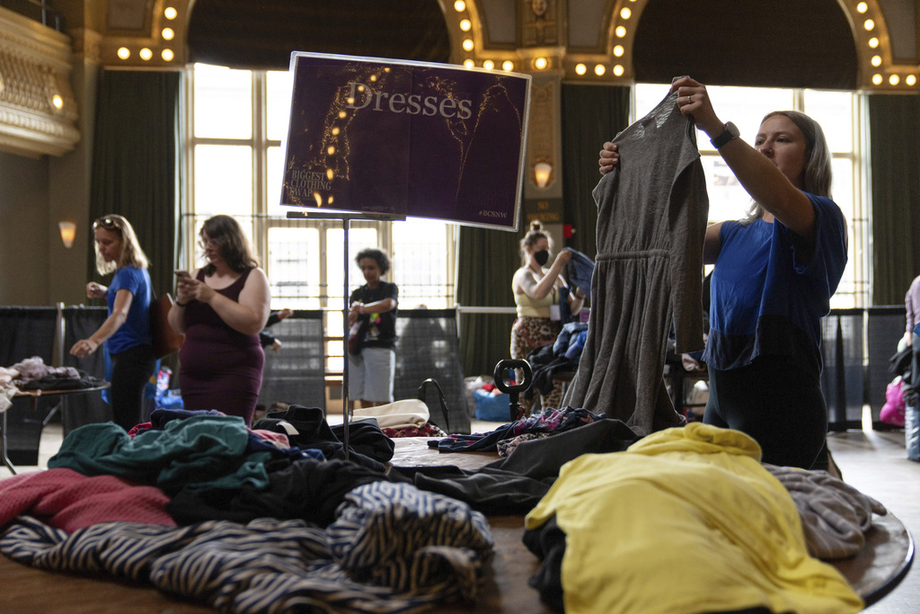 Carmen Nelson, right, looks at a dress during a clothing swap on Sunday, Sept. 14, 2025, in Portland, Ore. (AP Photo/Jenny Kane)