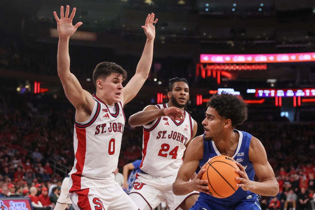 Creighton guard Nik Graves is defended by St. John's guard Dylan Darling (0) and forward Zuby Ejiofor (24) during the first half of an NCAA college basketball game, Saturday, Feb. 21, 2026, in New York. (AP Photo/Heather Khalifa)