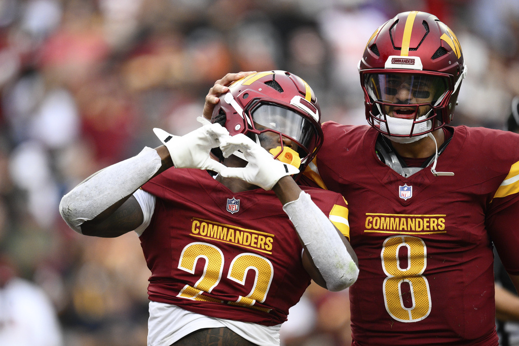 Washington Commanders running back Jacory Croskey-Merritt (22) celebrates with quarterback Marcus Mariota (8) after scoring a touchdown during the second half of NFL football game against the Las Vegas Raiders, Sunday, Sept. 21, 2025, in Landover, Md. (AP Photo/Nick Wass)
