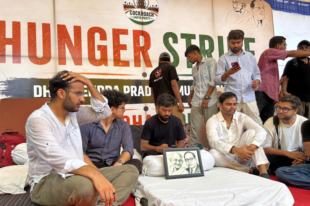 Abhijeet Dipke, founder of the Cockroach Janta Party, seated center, starts his indefinite hunger strike during a protest demanding the resignation of Education Minister Dharmendra Pradhan over alleged examination irregularities and repeated paper leaks in New Delhi, India, Saturday, July 18, 2026. (AP Photo/Shonal Ganguly)