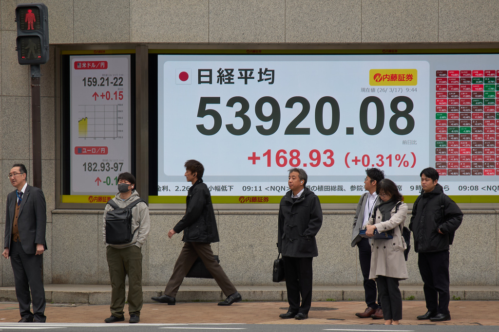 People stand in front of a stock price monitor showing Nikkei index at a security company Tuesday, March 17, 2026, in Tokyo. (AP Photo/Eugene Hoshiko)