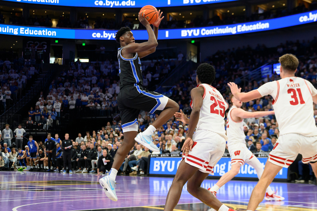 BYU forward AJ Dybantsa (3) shoots over Wisconsin guard John Blackwell (25) and forward Nolan Winter (31) during the first half of an NCAA college basketball game, Friday, Nov. 21, 2025, in Salt Lake City. (AP Photo/Tyler Tate)