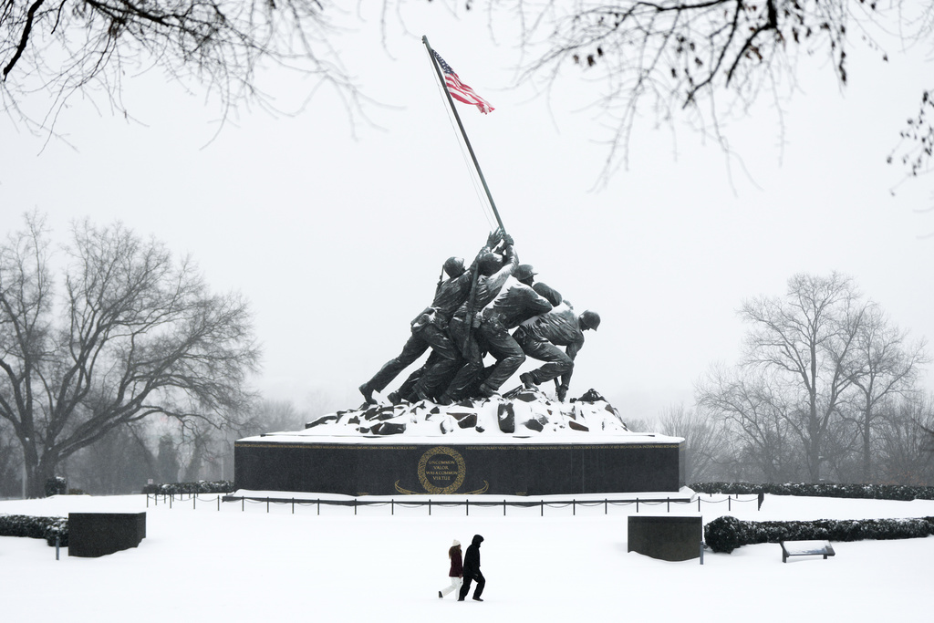 People walk past the Marine Corps War Memorial as snow falls, Sunday, Jan. 25, 2026, in Arlington, Va. (AP Photo/Julia Demaree Nikhinson)