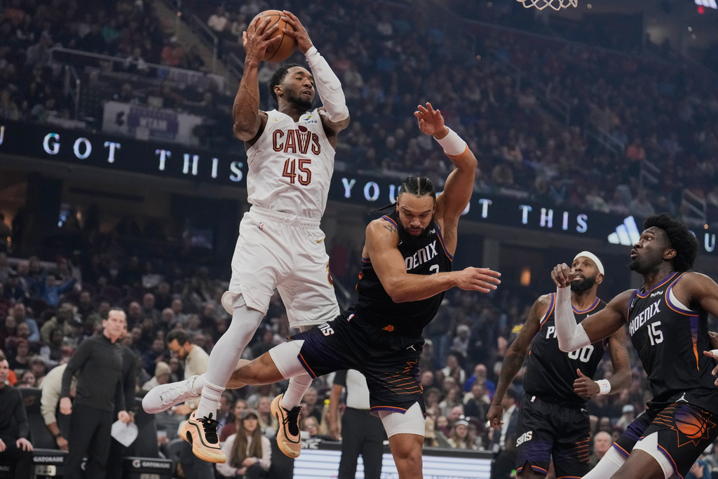 Cleveland Cavaliers guard Donovan Mitchell (45) catches a pass next to Phoenix Suns forward Dillon Brooks, center, forward Royce O'Neale (00) and center Mark Williams (15) in the first half of an NBA basketball game Wednesday, Dec. 31, 2025, in Cleveland. (AP Photo/Sue Ogrocki)