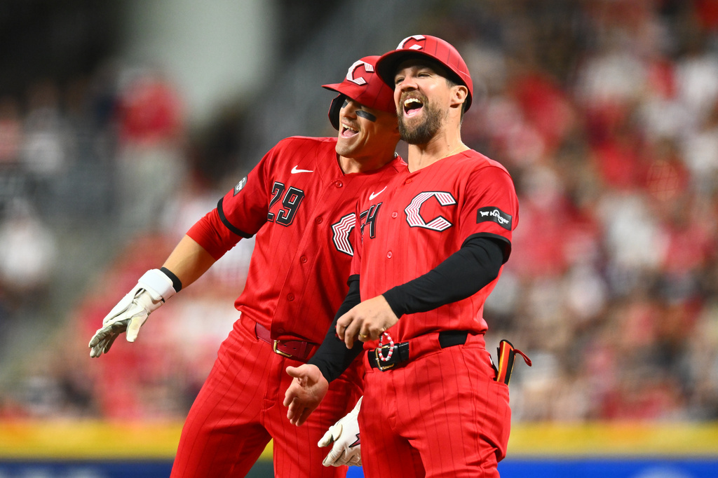 Cincinnati Reds' TJ Friedl, left, celebrates with first base coach Collin Cowgill after hitting a single during the sixth inning of a baseball game against the Detroit Tigers in Cincinnati, Saturday, April 25, 2026. (AP Photo/Ben Jackson)