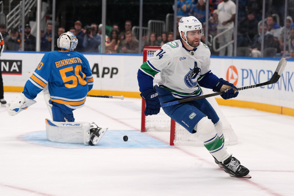 Vancouver Canucks' Jake DeBrusk (74) skates past St. Louis Blues goaltender Jordan Binnington (50) after scoring the game-winning goal in a shootout of an NHL hockey game Thursday, Oct. 30, 2025, in St. Louis. (AP Photo/Jeff Roberson)