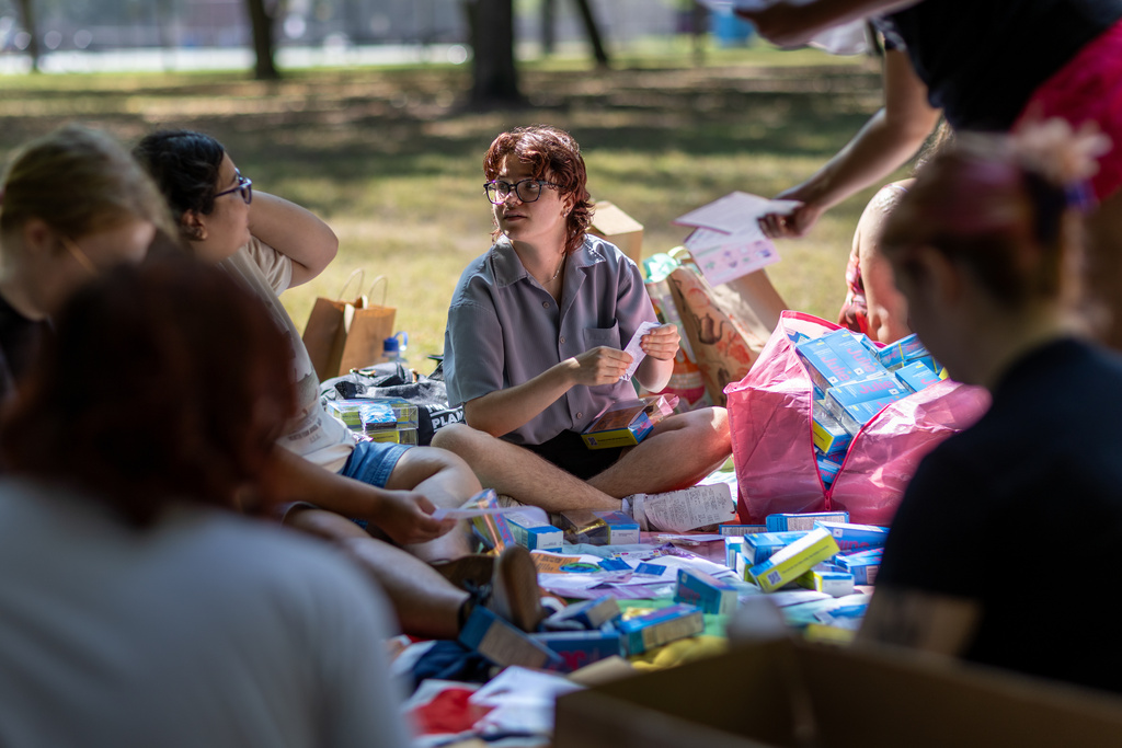 DePaul University senior Mak Roban, 20, center, assembles a kit of contraceptive supplies at Oz Park in Chicago on Sunday, Sept. 28, 2025. (AP Photo/Heidi Zeiger)