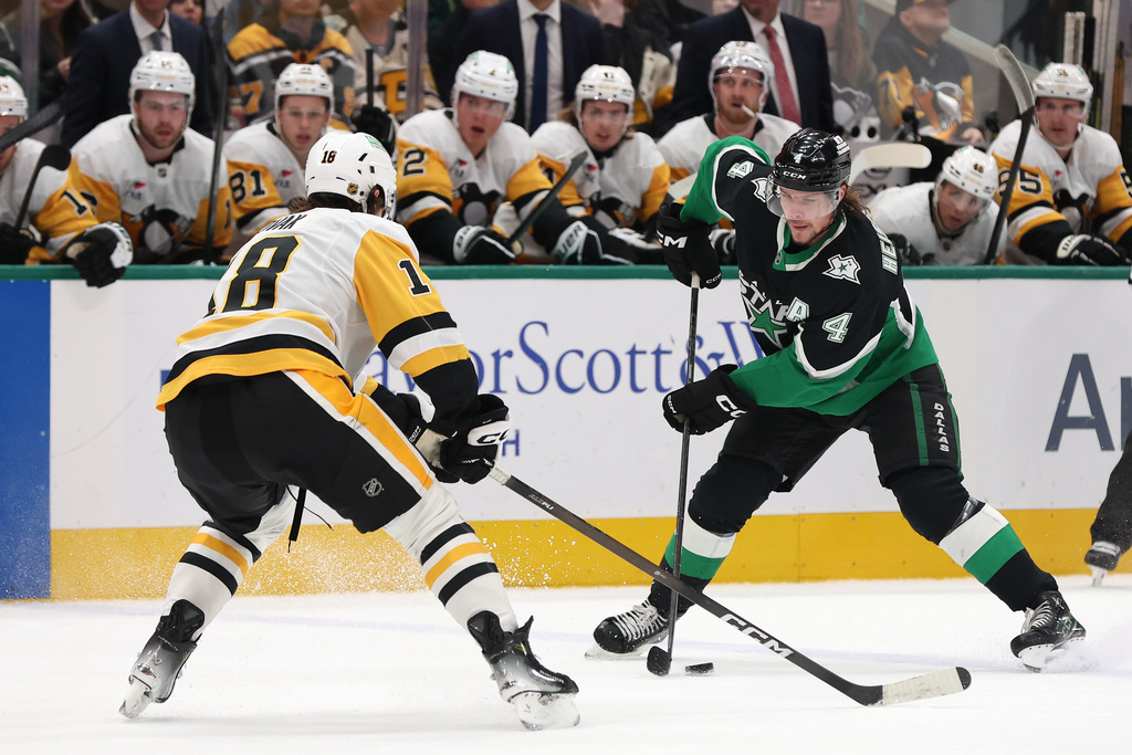 Dallas Stars defenseman Miro Heiskanen (4) is defended by Pittsburgh Penguins center Tommy Novak (18) during the first period of an NHL hockey game Sunday, Dec. 7, 2025, in Dallas. (AP Photo/Sam Hodde)