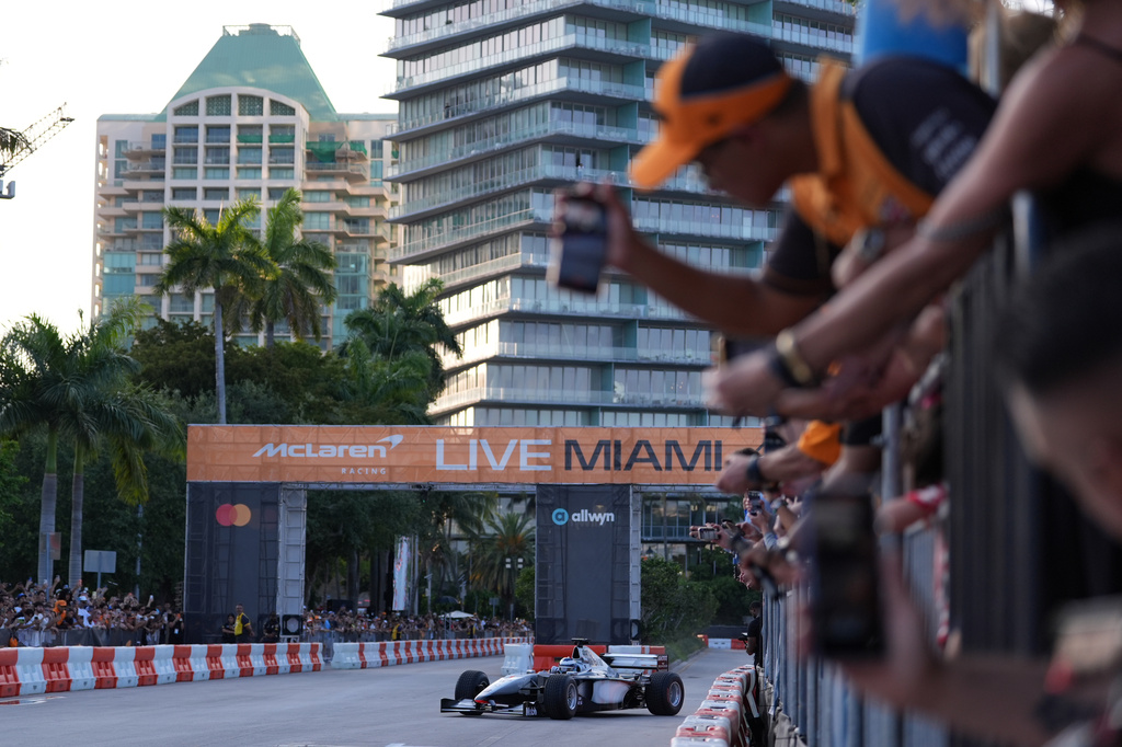 Fans watch as former Brazilian racing driver Bruno Senna steers an MP4/6 during a fan event showcasing past McLaren race cars ahead of the Formula One Miami Grand Prix auto race, Wednesday, April 29, 2026, in the Coconut Grove area of Miami. (AP Photo/Rebecca Blackwell)