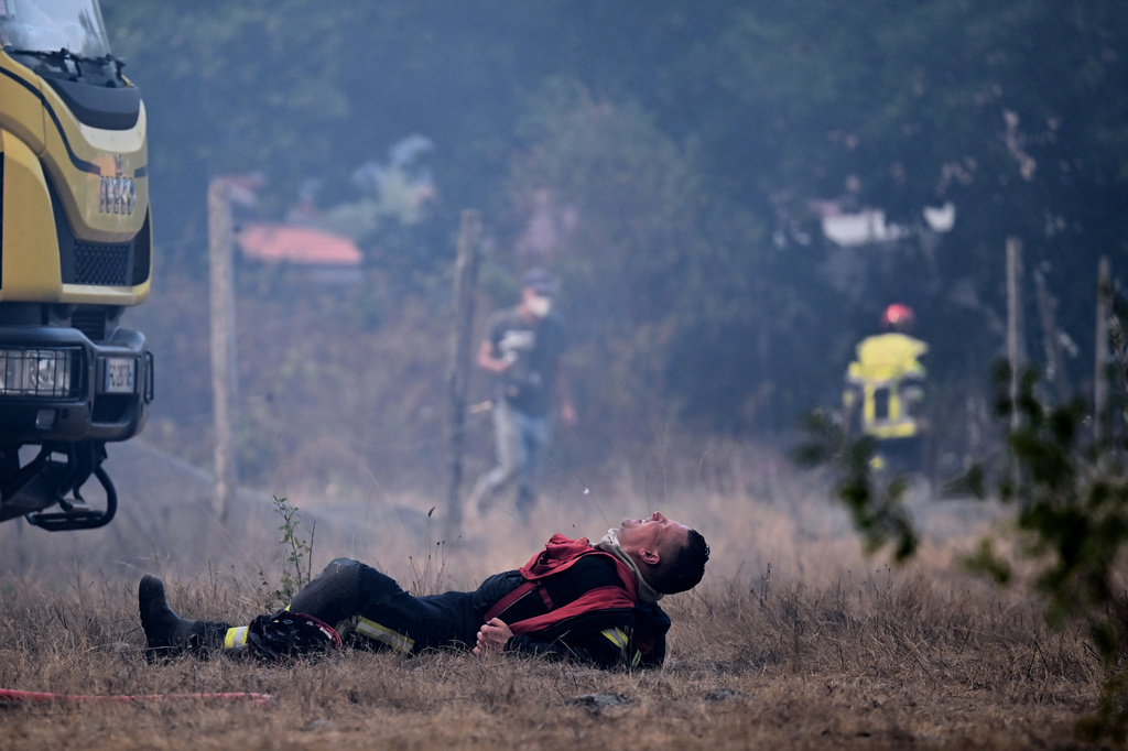 A firefighter lays on the ground after working to extinguish a fire in the forest near Blagon, during wildfires in southwestern France, Wednesday, July 29, 2026. (AP Photo/Emma Da Silva)