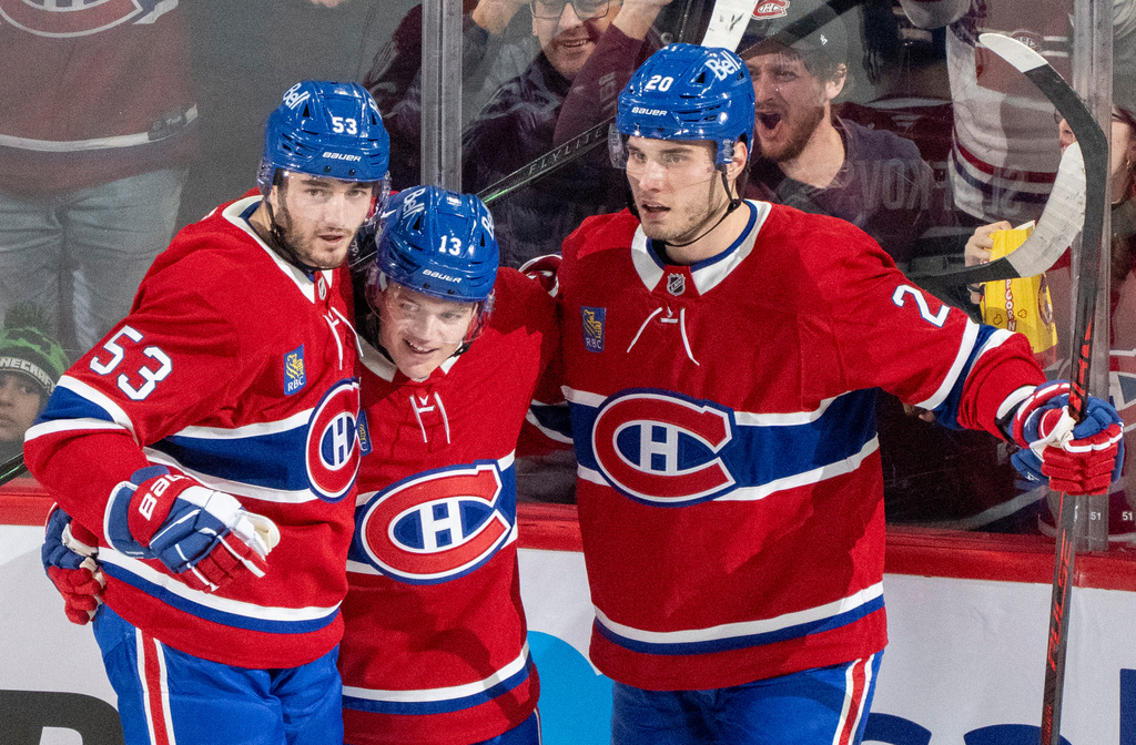 Montreal Canadiens' Cole Caufield (13) celebrates his goal on the Carolina Hurricanes with teammates Noah Dobson (53) and Juraj Slafkovsky (20) during the second period of an NHL hockey game in Montreal on Tuesday, March 24, 2026. (Christinne Muschi/The Canadian Press via AP)