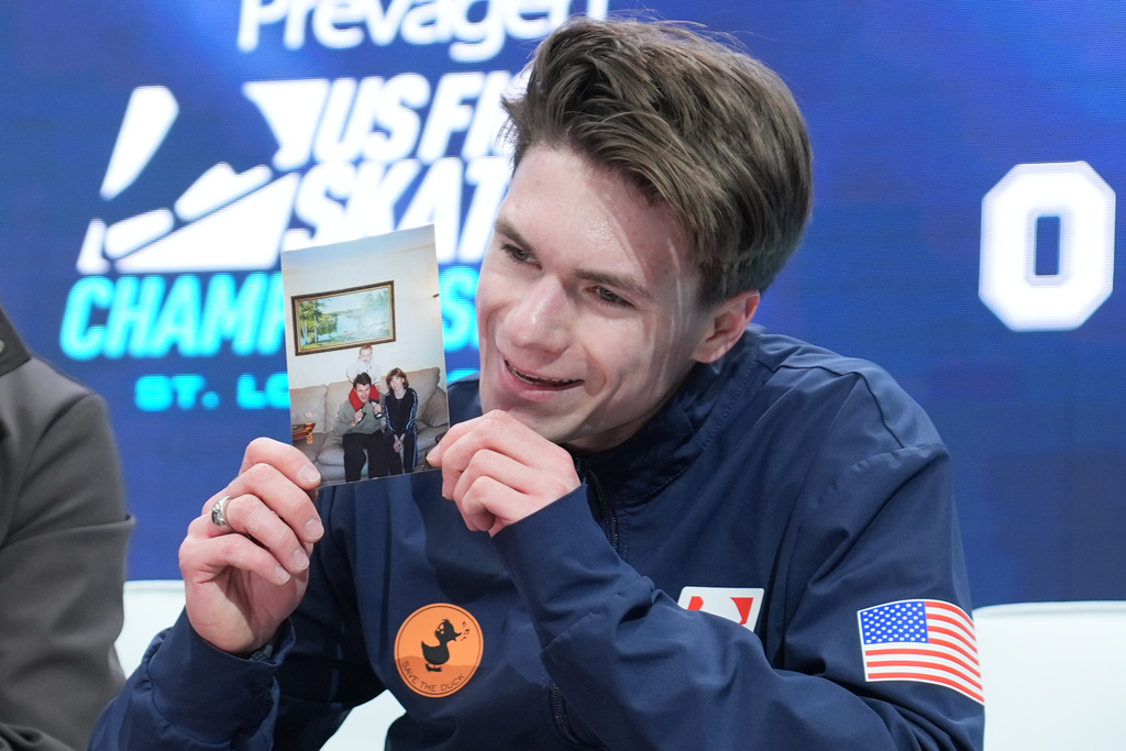 Maxim Naumov holds a photo of his parents after competing during the men's free skate competition at the U.S. Figure Skating Championships, Saturday, Jan. 10, 2026, in St. Louis. (AP Photo/Stephanie Scarbrough)