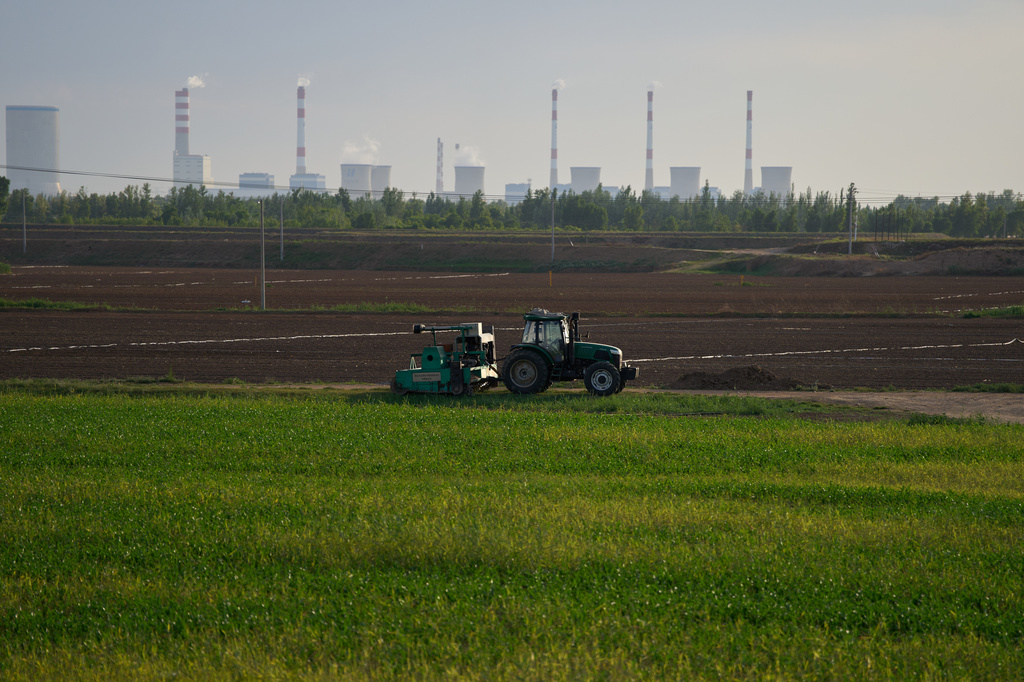 A tractor is visible on a field near power plants near Ordos in northern China's Inner Mongolia province on Thursday, June 11, 2026. (AP Photo/Ng Han Guan)