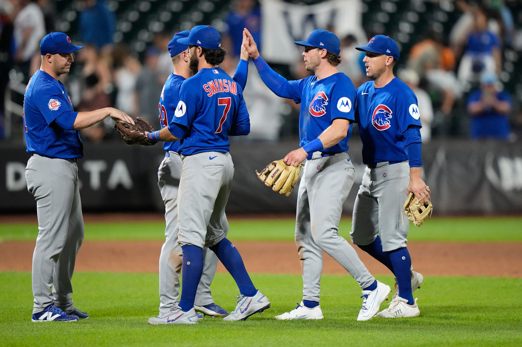 Chicago Cubs' Dansby Swanson (7) hands the game ball to pitcher Jacob Webb as they celebrate with teammates after the second baseball game of a doubleheader against the New York Mets Wednesday, June 24, 2026, in New York. (AP Photo/Frank Franklin II)