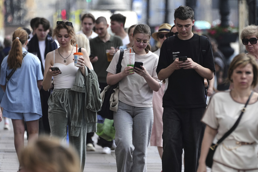 Pedestrians look at their phones while walking through St. Petersburg, Russia, on Monday, July 14, 2025. (AP Photo/Dmitri Lovetsky)