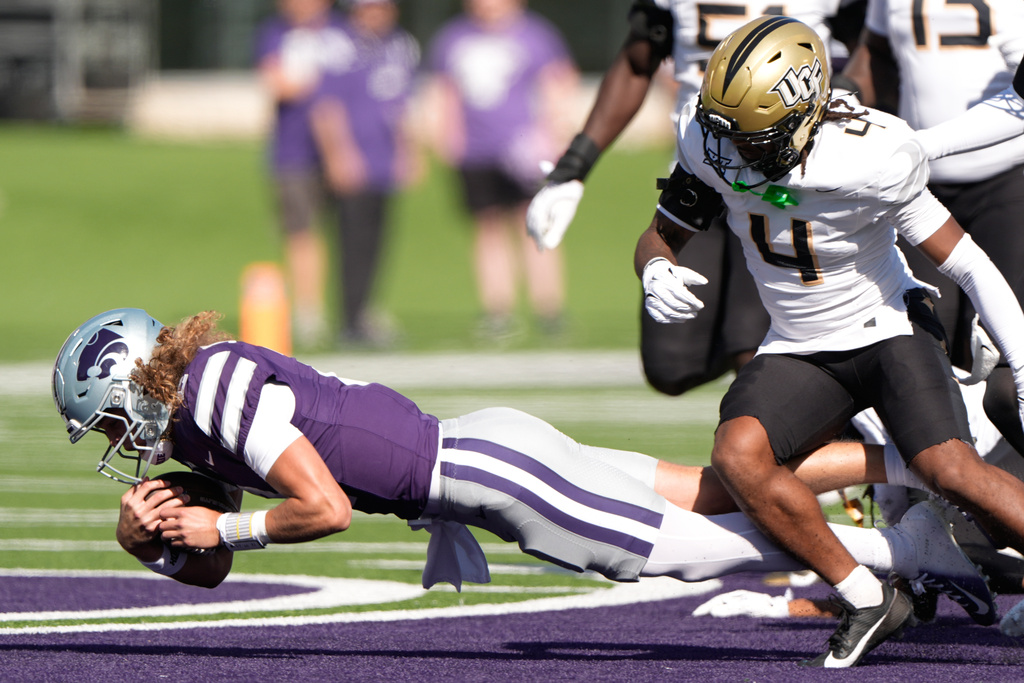 Kansas State quarterback Avery Johnson, left, is tackled by Central Florida defensive back Braeden Marshall (4) during the first half of an NCAA college football game Saturday, Sept. 27, 2025, in Manhattan, Kan. (AP Photo/Charlie Riedel)