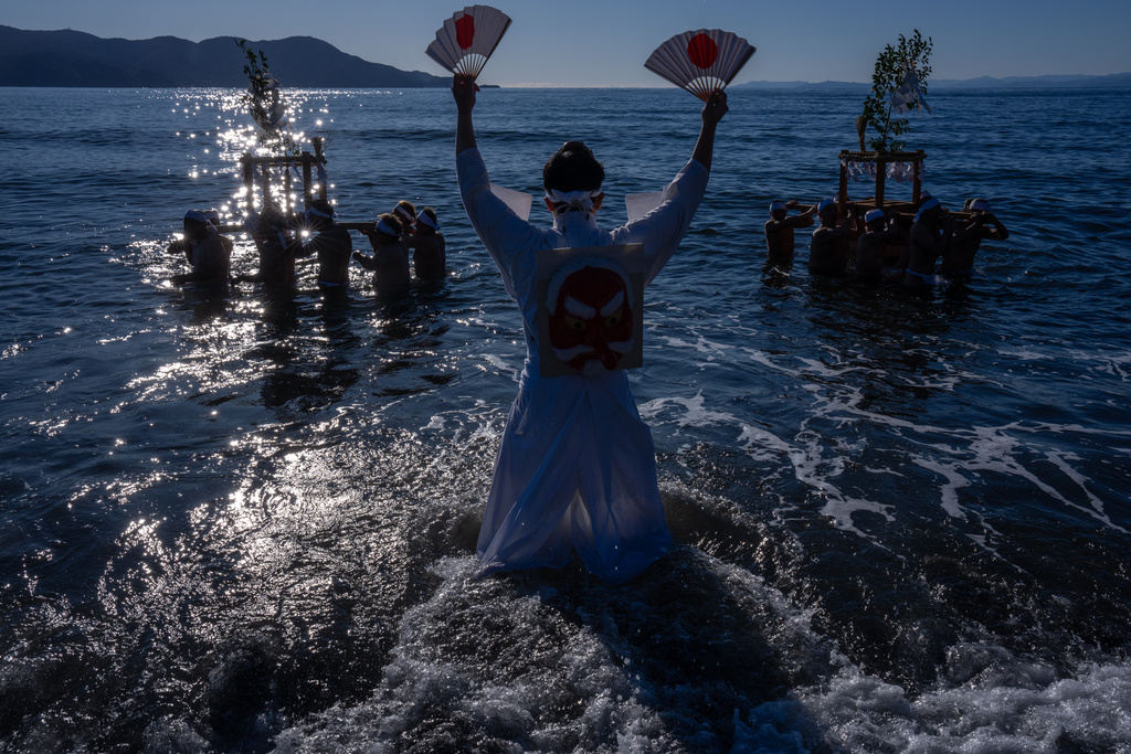 Participants carry a portable shrine 'mikoshi', during the Winter Sea Misogi Festival, a Shinto purification ritual marking the New Year, in Numazu, Japan, Monday, Jan. 12, 2026. (AP Photo/Louise Delmotte)