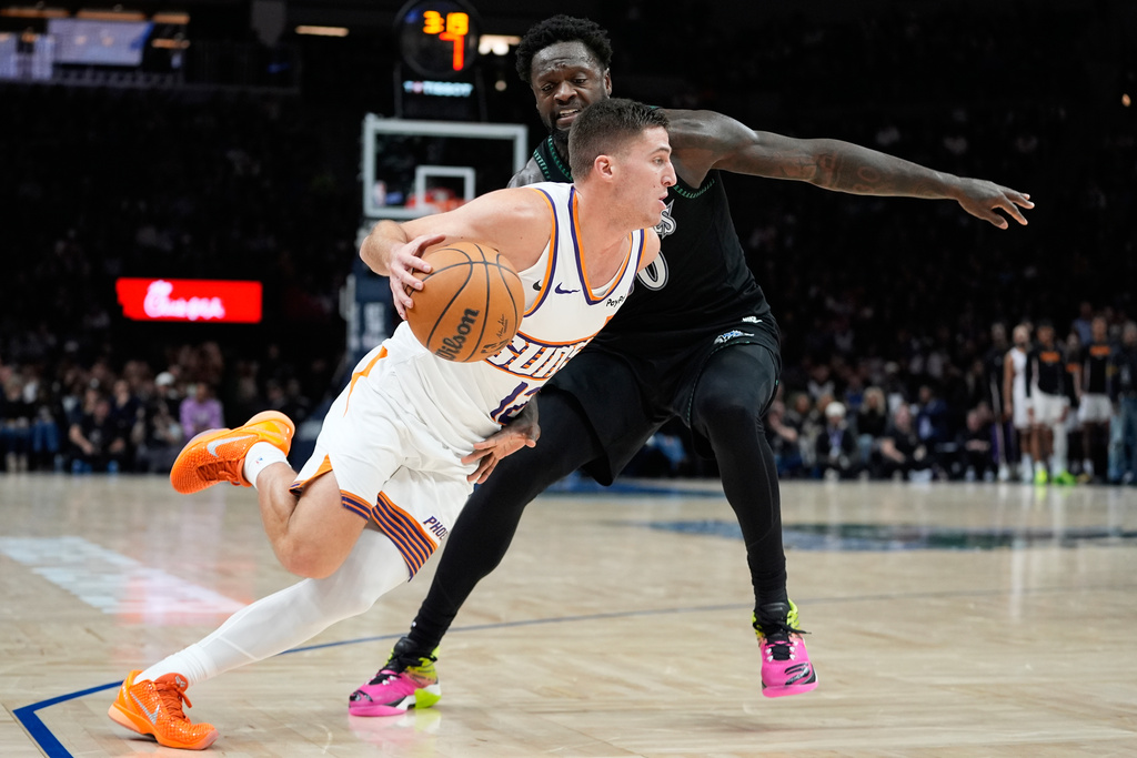 Phoenix Suns guard Collin Gillespie, front, works toward the basket as Minnesota Timberwolves forward Julius Randle defends during the second half of an NBA basketball game, Monday, Dec. 8, 2025, in Minneapolis. (AP Photo/Abbie Parr)