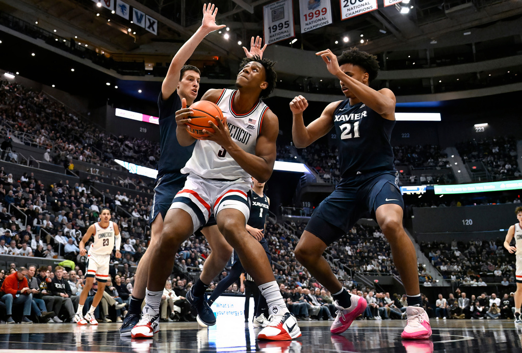 UConn forward Tarris Reed Jr., center, looks to shoot between Xavier forward Filip Borovicanin, left, and Xavier forward Anthony Robinson, right, in the first half of an NCAA college basketball game, Tuesday, Feb. 3, 2026, in Hartford, Conn. (AP Photo/Jessica Hill)