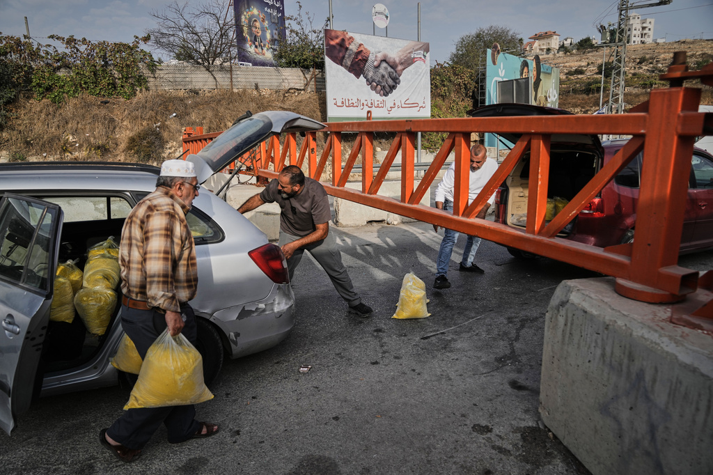 Palestinians transport bags of semolina past a military gate closed to vehicles during an Israeli army operation in Hebron, in the occupied West Bank, Saturday, Oct. 24, 2026, a day after a Palestinian shooting attack in the area. (AP Photo/Mahmoud Illean)