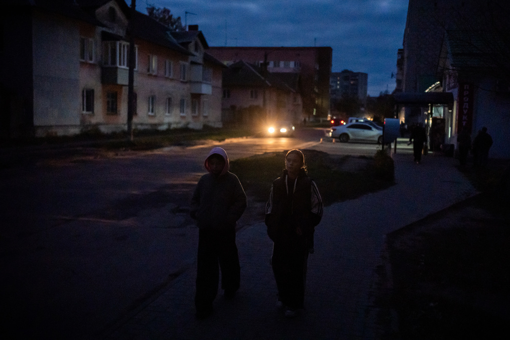 Kids walk along a dark residential street during a rolling blackout, Thursday, Oct. 16, 2025, in Shostka, Ukraine. (AP Photo/Julia Demaree Nikhinson)