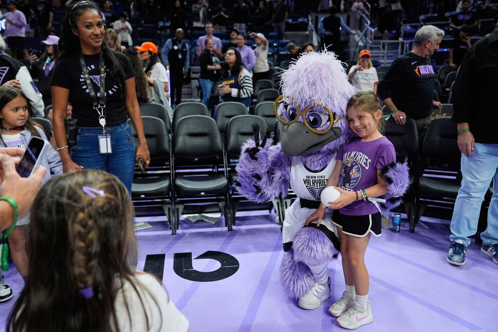 Violet, the Golden State Valkyries mascot, has a photo taken with a fan after the team's victory over the Indiana Fever in a WNBA basketball game Sunday, Sept. 31, 2025, in San Francisco. (AP Photo/Godofredo A. Vásquez)