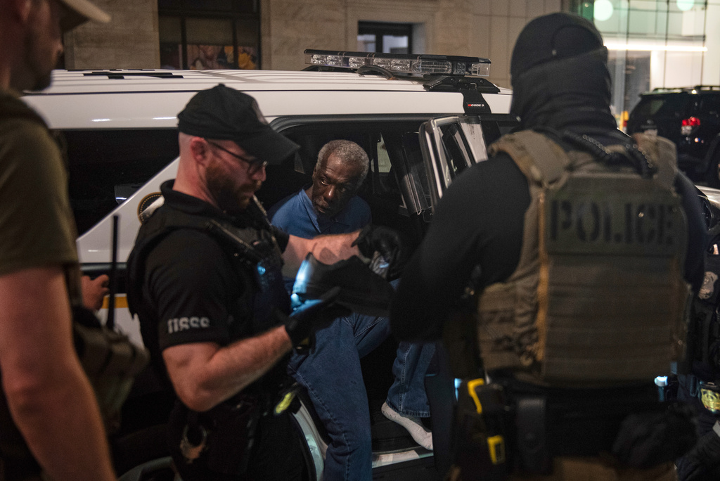 U.S. Secret Service agents, with the help of FBI agents, take a man into custody, center, near a homeless encampment in downtown Washington, Thursday, Aug. 14, 2025. (AP Photo/Cliff Owen)