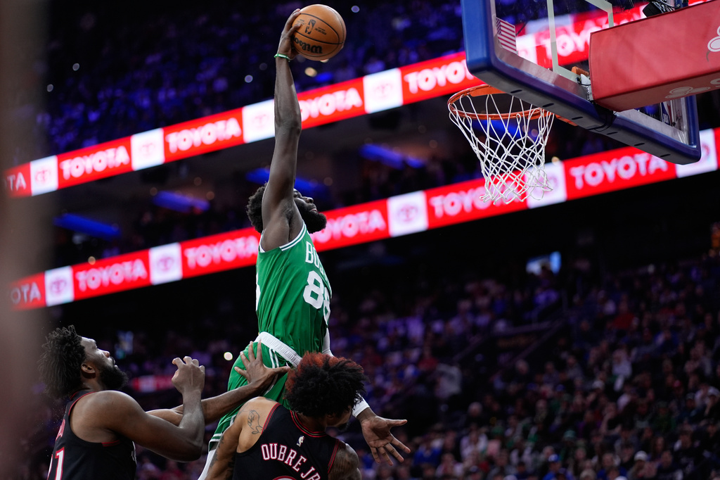 FILE - Boston Celtics' Neemias Queta, top, goes up for a dunk over Philadelphia 76ers' Kelly Oubre Jr., right, and Joel Embiid during the first half of Game 4 in a first-round NBA basketball playoffs series April 26, 2026, in Philadelphia. (AP Photo/Matt Slocum, File)
