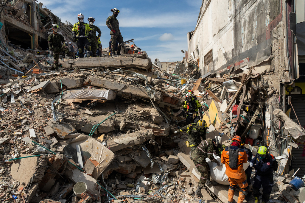 Rescuers carry the body of a victim from the rubble four days after after an earthquake hit Pereira, Colombia, Friday, Aug. 14, 2026. (AP Photo/Brandon Pinto)