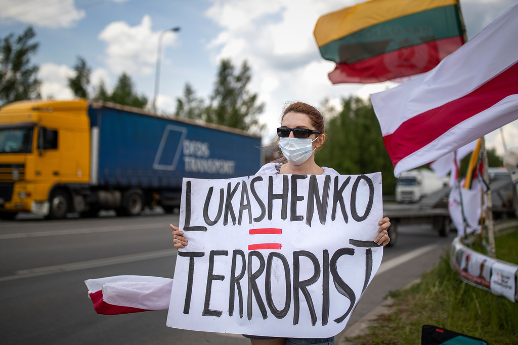 FILE - A protester holds a banner, old Belarusian and Lithuanian national flags during a protest demanding freedom for political prisoners in Belarus near Medininkai, Lithuanian-Belarusian border crossing point east of Vilnius, Lithuania, Tuesday, June 8, 2021. (AP Photo/Mindaugas Kulbis, File)