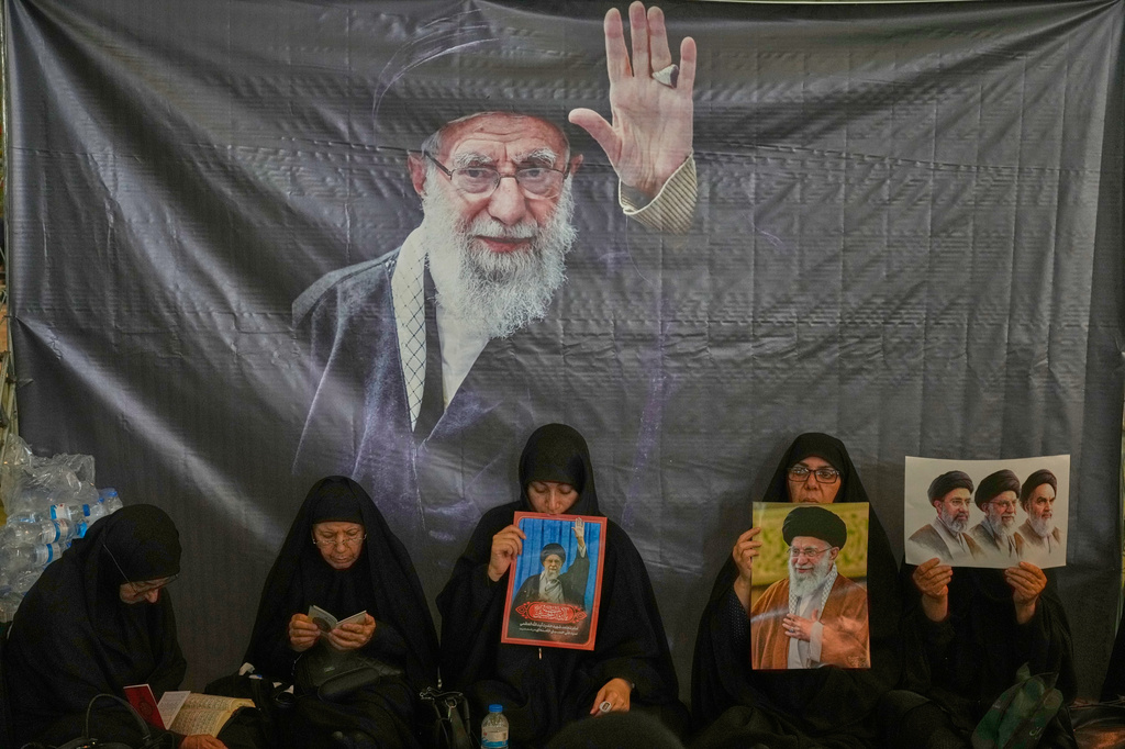 Women sit beneath a portrait of the late Supreme Leader Ali Khamenei as mourners gather to commemorate the late leader at the Imam Khomeini Mosalla Grand Mosque in Tehran, Iran, Tuesday, July 14, 2026. (AP Photo/Vahid Salemi)