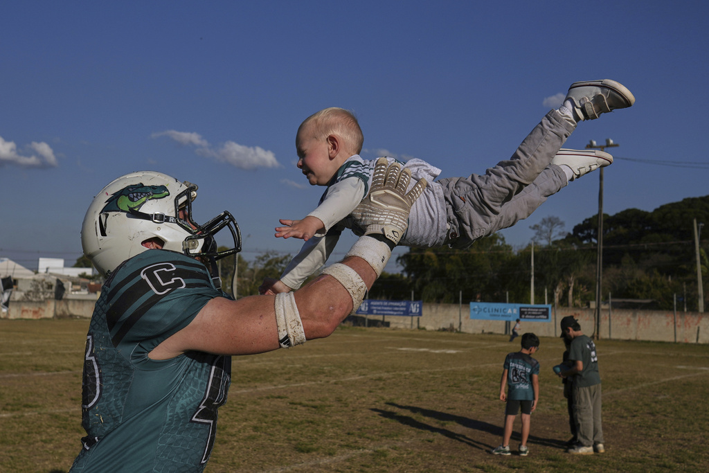 The Coritiba Crocodiles' Cleverson Kvas, a survivor of the 2024 team bus crash that killed three athletes, plays with his son Andre after a football game against the Brown Spiders in Curitiba, Brazil, Sunday, Aug. 17, 2025. (AP Photo/Andre Penner)