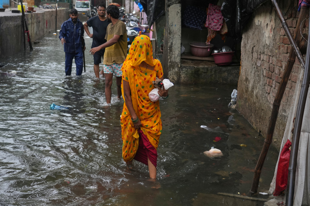 A woman walks through a waterlogged slum following monsoon rains in Mumbai, India, Wednesday, June 24, 2026. (AP Photo/Rafiq Maqbool)