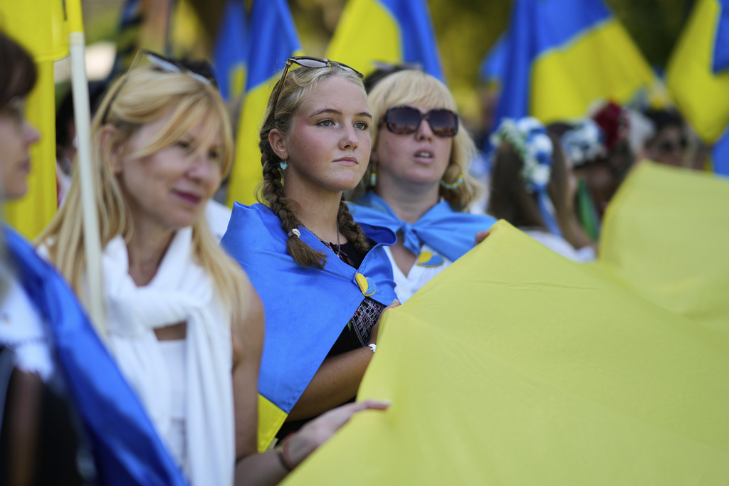 Ukrainian women help hold a giant national flag before marching down Liberdade Avenue in Lisbon in a demonstration to mark Ukraine's Independence Day, Sunday, Aug. 24, 2025. (AP Photo/Armando Franca)