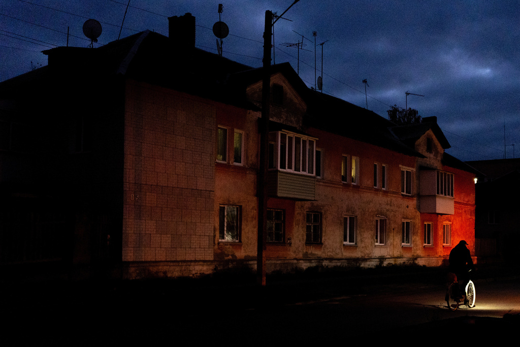 A person rides a bike along a dark residential street during a rolling blackout, Thursday, Oct. 16, 2025, in Shostka, Ukraine. (AP Photo/Julia Demaree Nikhinson)