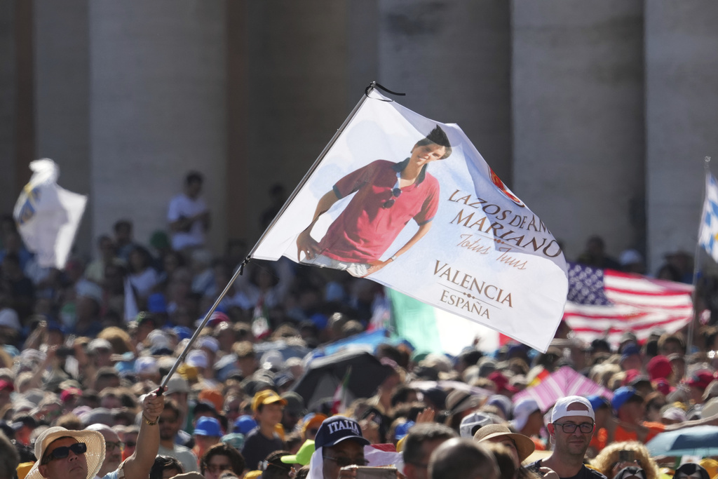 A flag featuring the image of Carlo Acutis is waved during the canonization Mass of Carlo Acutis and Pier Giorgio Frassati in St. Peter's Square at the Vatican on Sunday, Sept. 7, 2025. (AP Photo/Andrew Medichini)