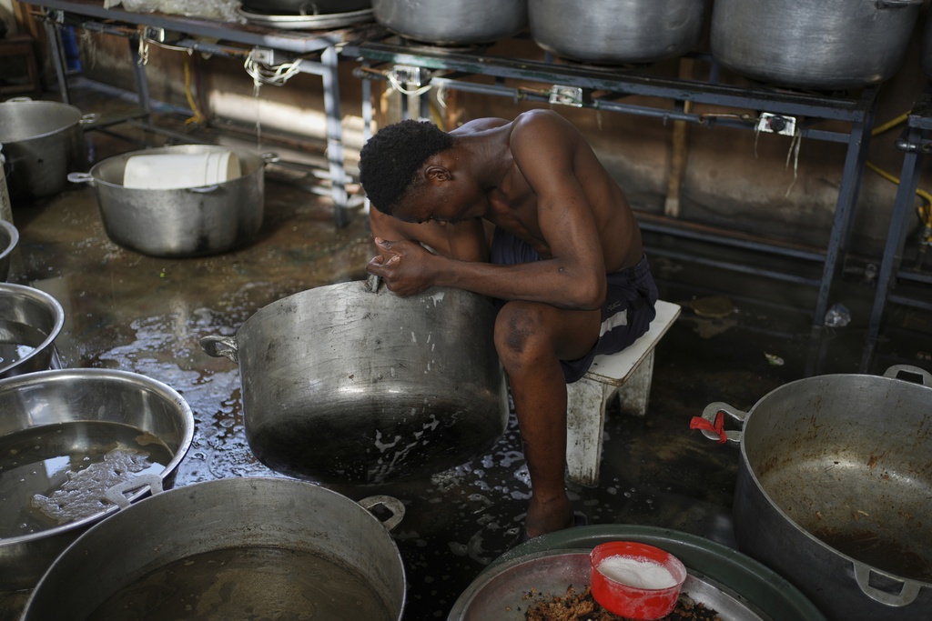 A man cleans pots at a makeshift shelter for people displaced by gang violence in Port-au-Prince, Haiti, Wednesday, Sept. 17, 2025. (AP Photo/Odelyn Joseph)