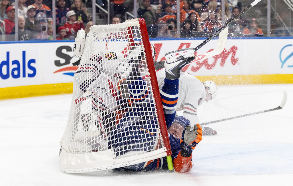 Chicago Blackhawks goalie Spencer Knight (30) makes the save as Sam Rinzel (6) and Edmonton Oilers' Trent Frederic (10) crash the net during the second period of an NHL game, in Edmonton on Thursday April 2, 2026. (Jason Franson/The Canadian Press via AP)